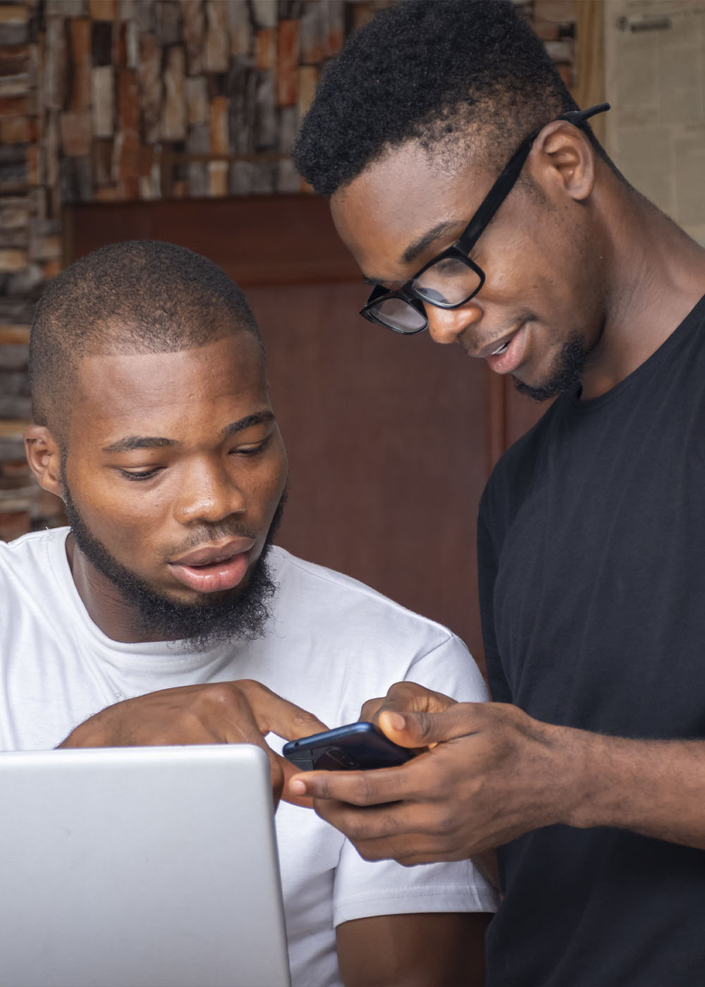 Group of young african males discussing a project while using their laptop and phones